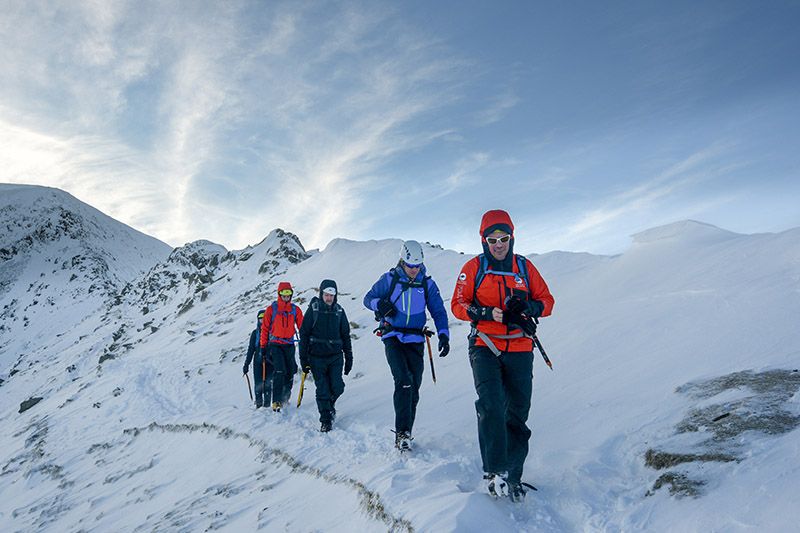 A group course on a gentle descent down a snow covered fell.